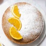 Top down view of cake topped with powdered sugar and sliced oranges.