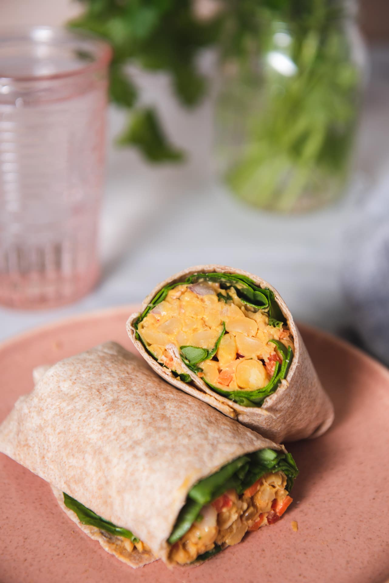 Two halves of a chickpea wrap on a pink plate/