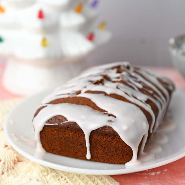 Gingerbread loaf on a white plate dripping with light pink icing.
