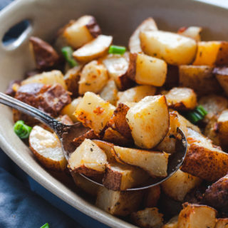 Close up view of the crispy potatoes being scooped with a spoon.