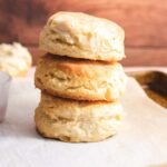 Three vegan biscuits stacked on top of each other in front of a wood background.