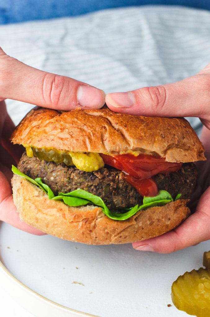 Close up view of hands holding a veggie burger. 