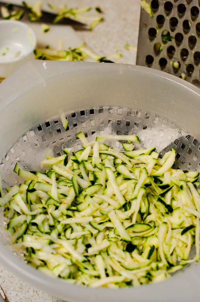 Coarsely grated zucchini in a plastic colander