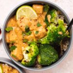 Overhead view of gray bowl with broccoli, peanut tofu and a lime wedge