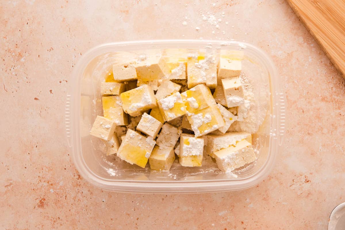 Plastic container filled with cubed tofu, corn starch and olive oil