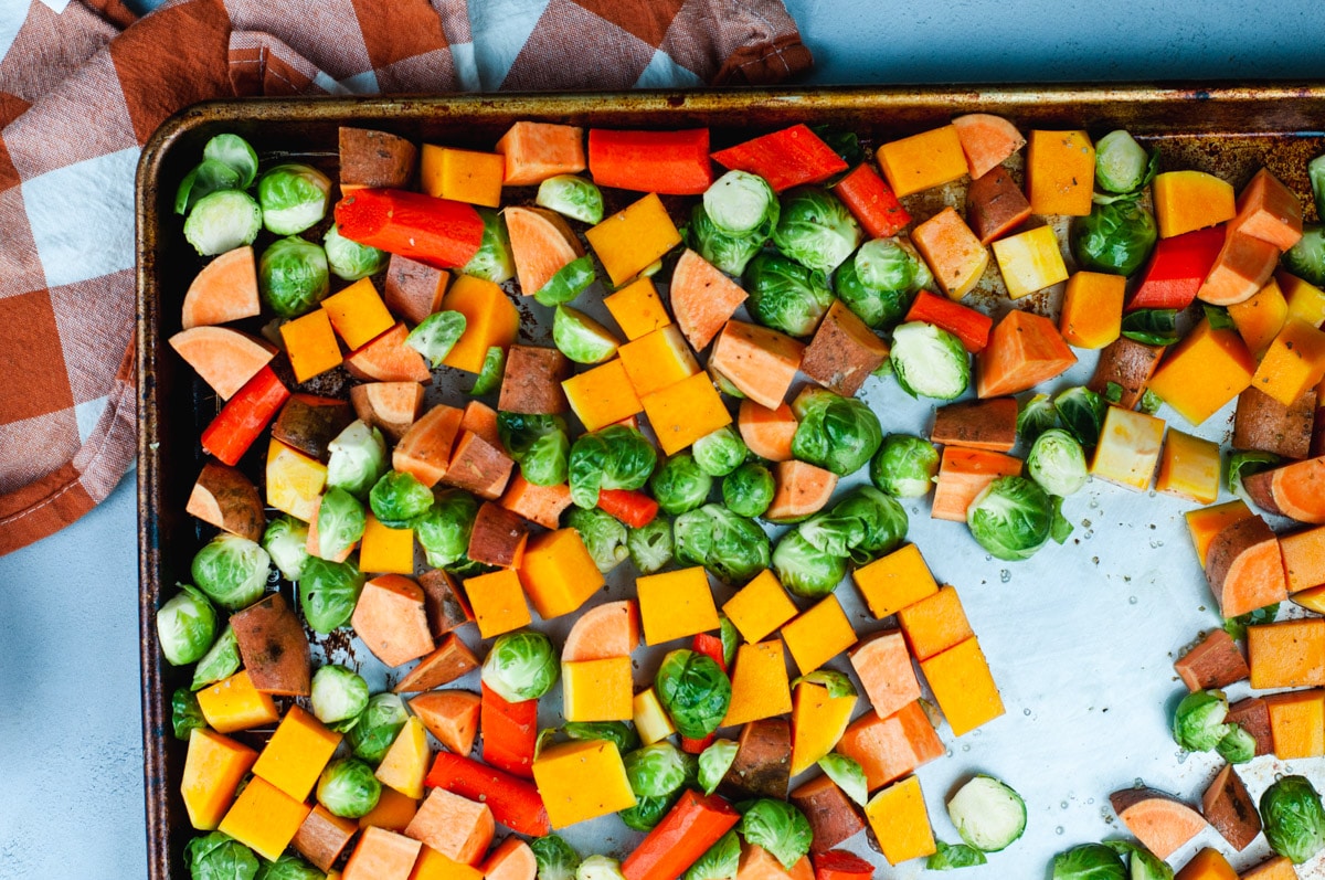 Uncooked vegetables lined up evenly on a metal sheet pan.