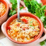 Pink bowl with barley soup topped with Parmesan.