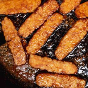 Close up of sliced tempeh in a black cast iron skillet