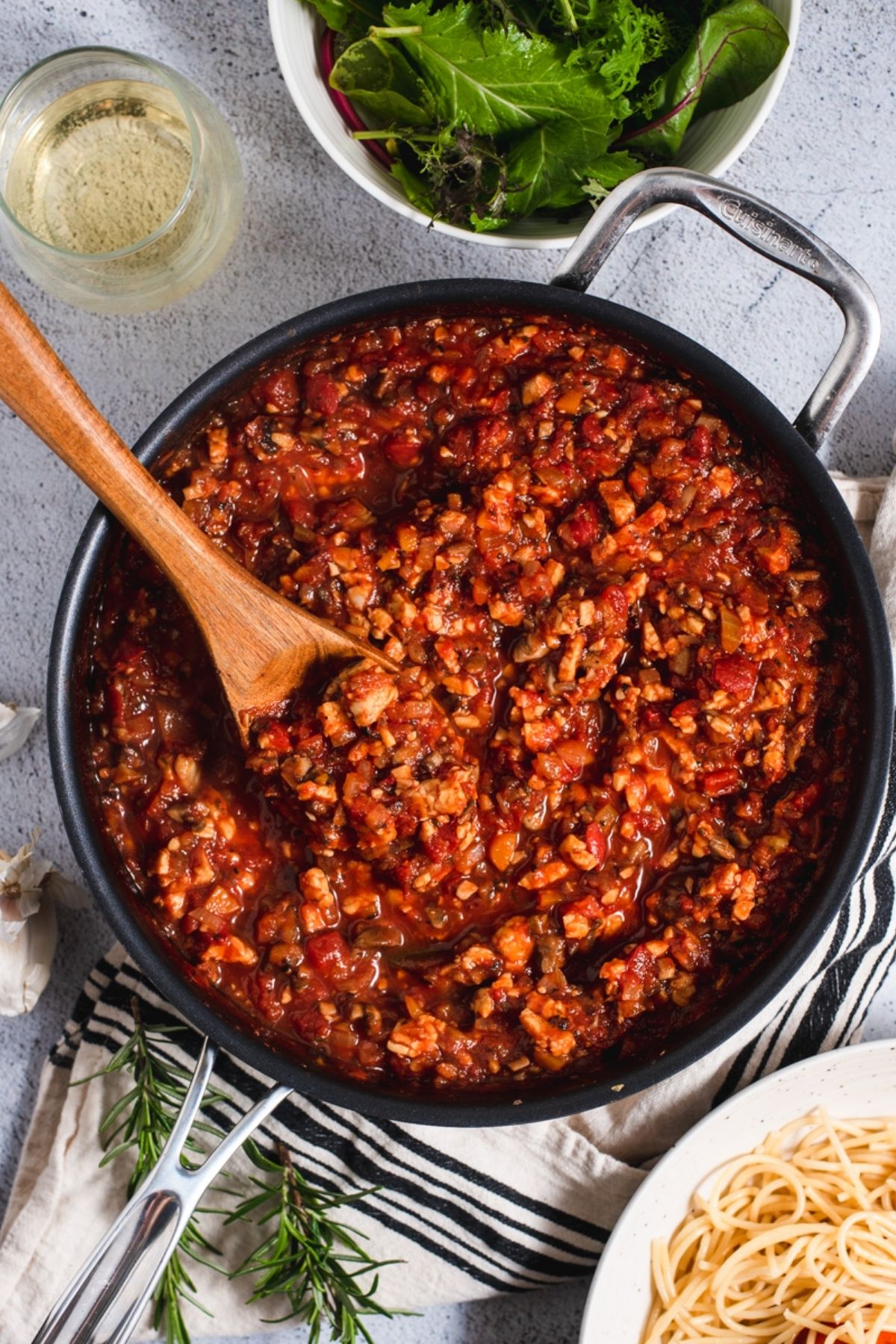 Tempeh Bolognese sauce in a large black skillet with a wooden spoon.