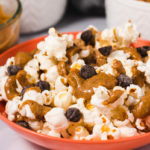 Orange bowl filled with popcorn, walnut butter and chocolate chips