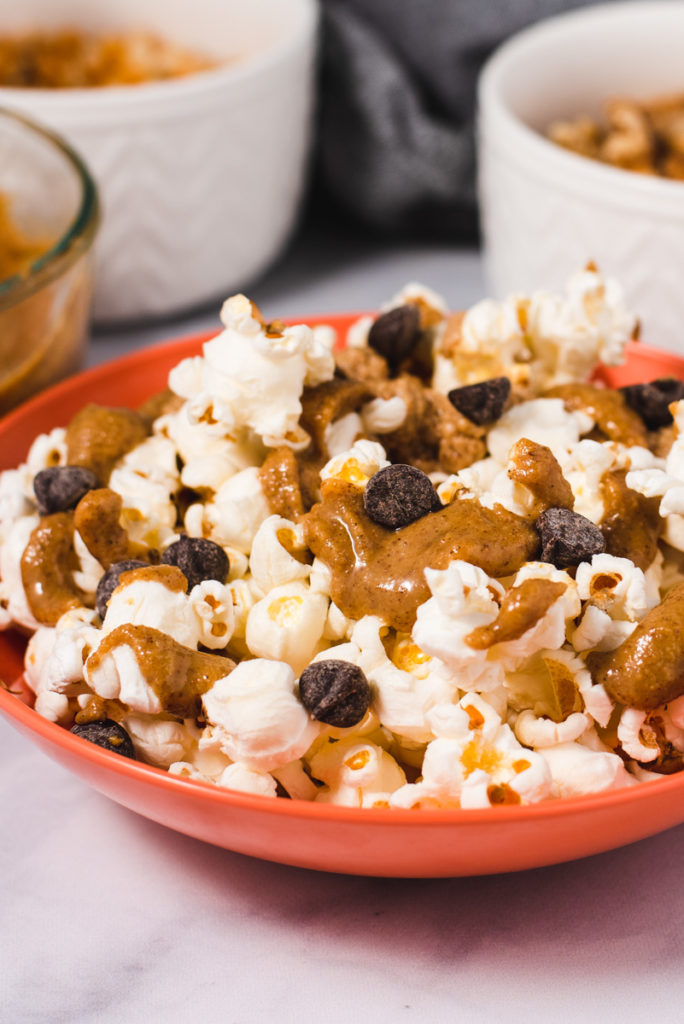 Orange bowl filled with popcorn, walnut butter and chocolate chips