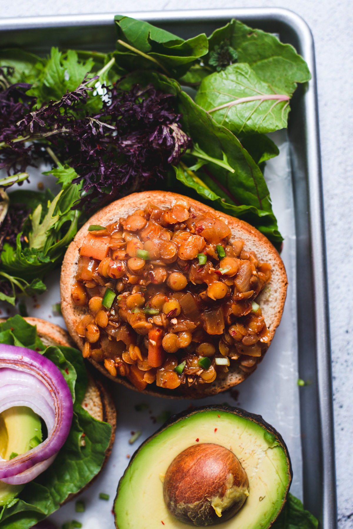 Lentils piled on whole wheat bun surrounded by lettuce.