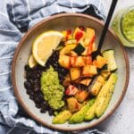 Bowl filled with pesto, avocado, roasted potatoes, black beans and roasted squash.