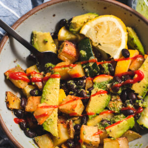 Gray bowl filled with roasted vegetables and black beans.