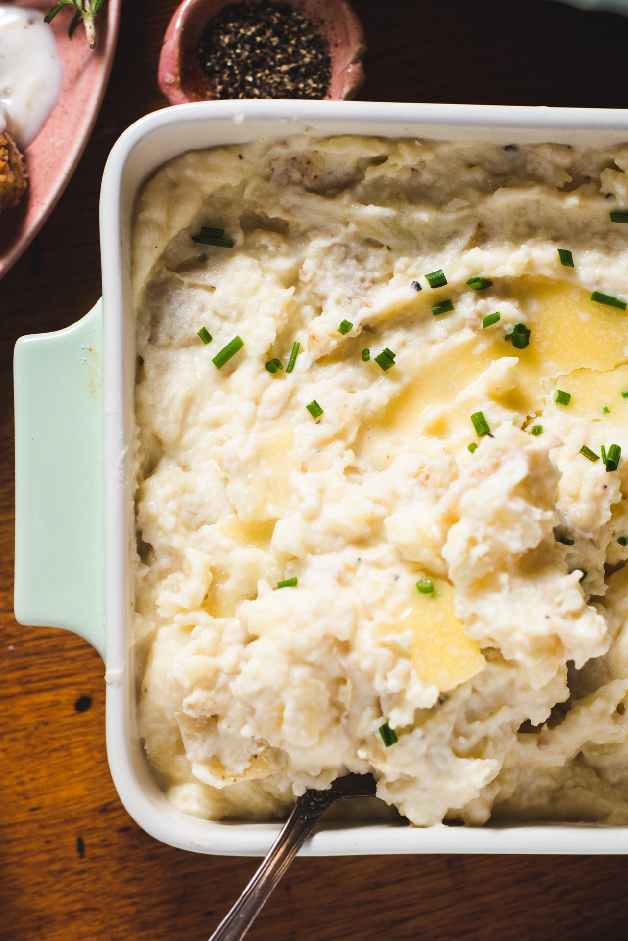 Close up of mashed potatoes in green casserole dish.
