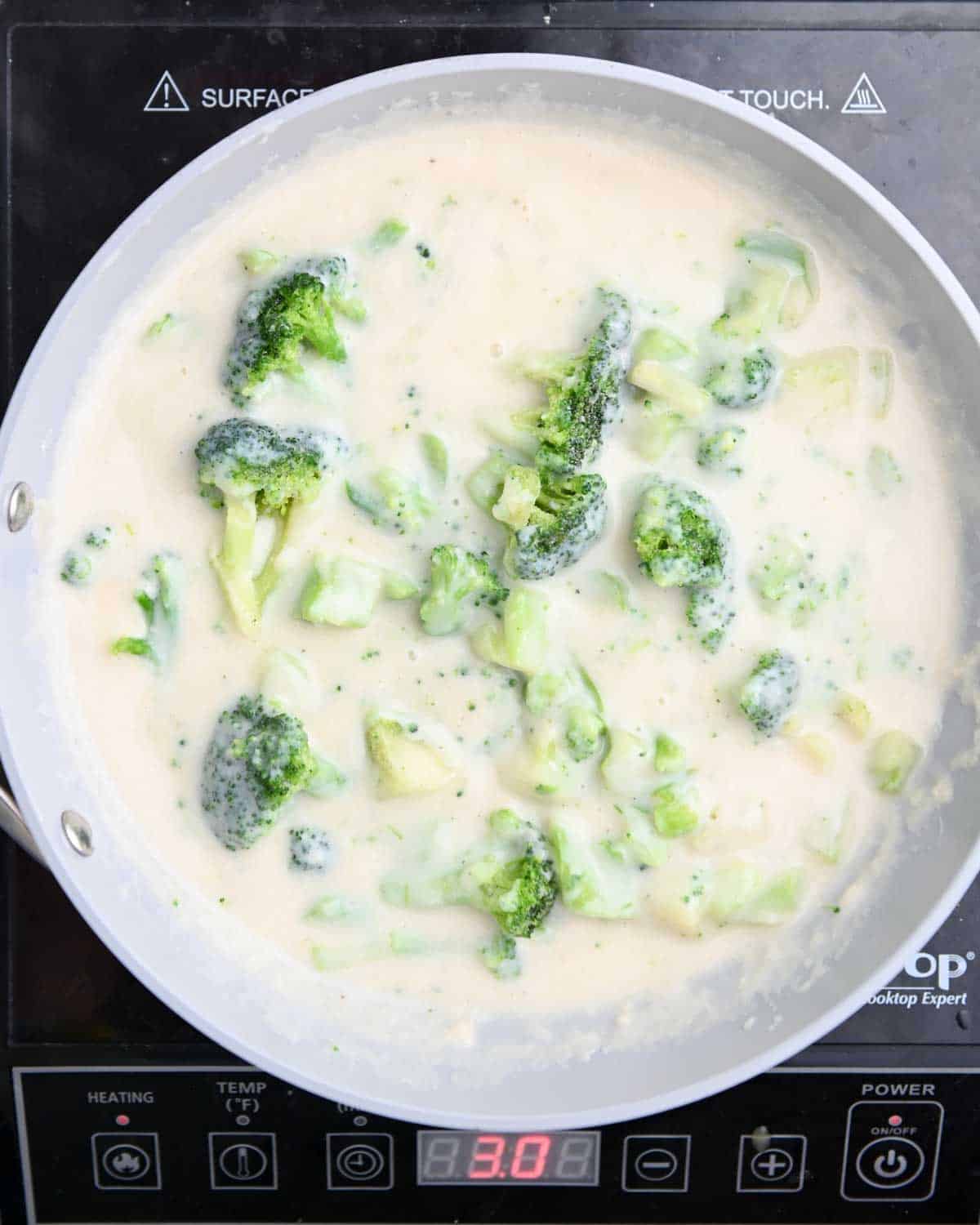 Broccoli in a creamy sauce in a gray skillet.