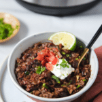 Bowl of rice and beans topped with salsa, sour cream and cilantro