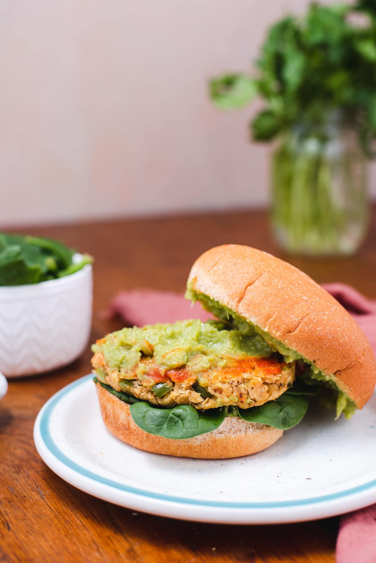 Veggie patty topped with guacamole on a bun.