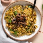 Orzo with mushrooms in white speckled bowl