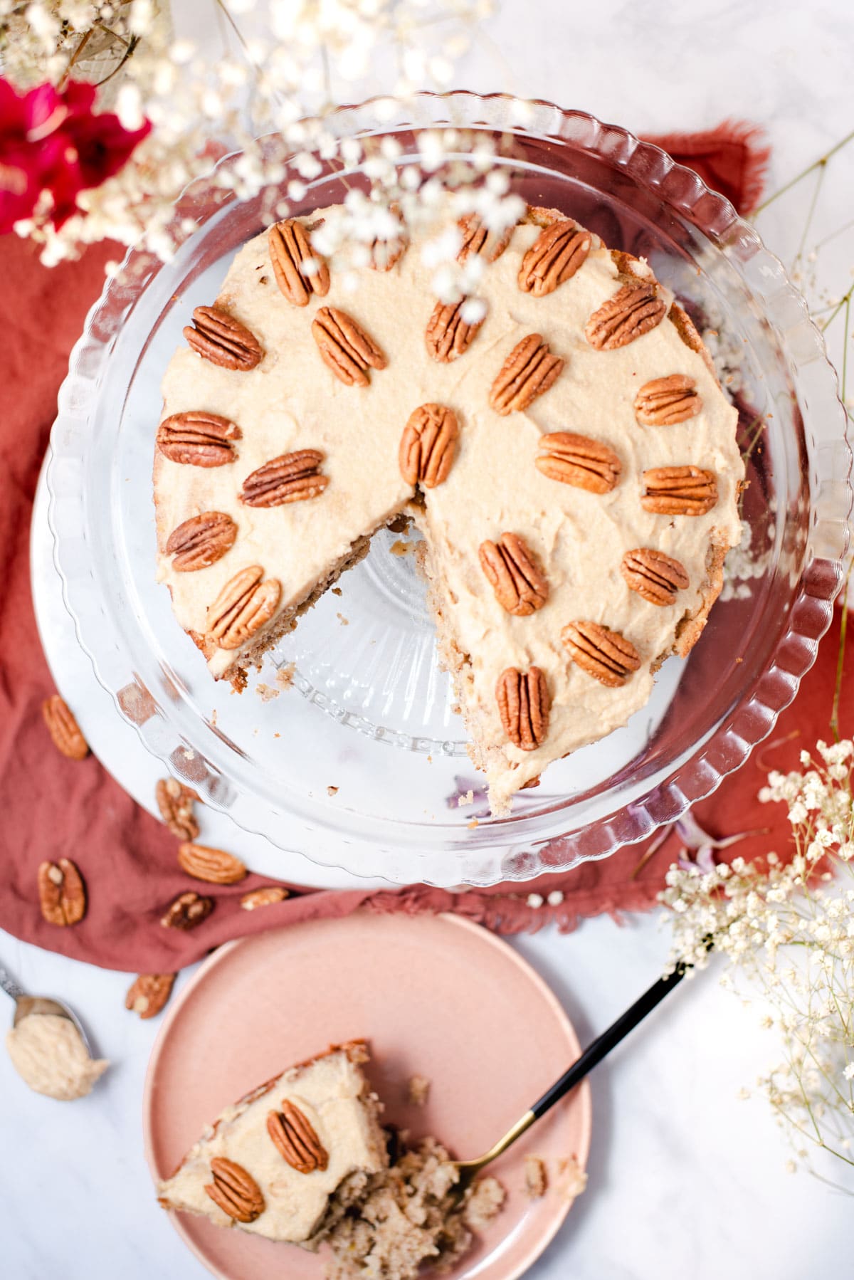 Overhead view of cake topped with pecans on a glass cake stand.