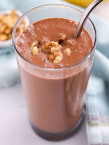 View of top of chocolate banana smoothie in a tall glass.