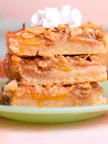 Three peach bars stacked on top of each other with a dollop of whipped cream on top