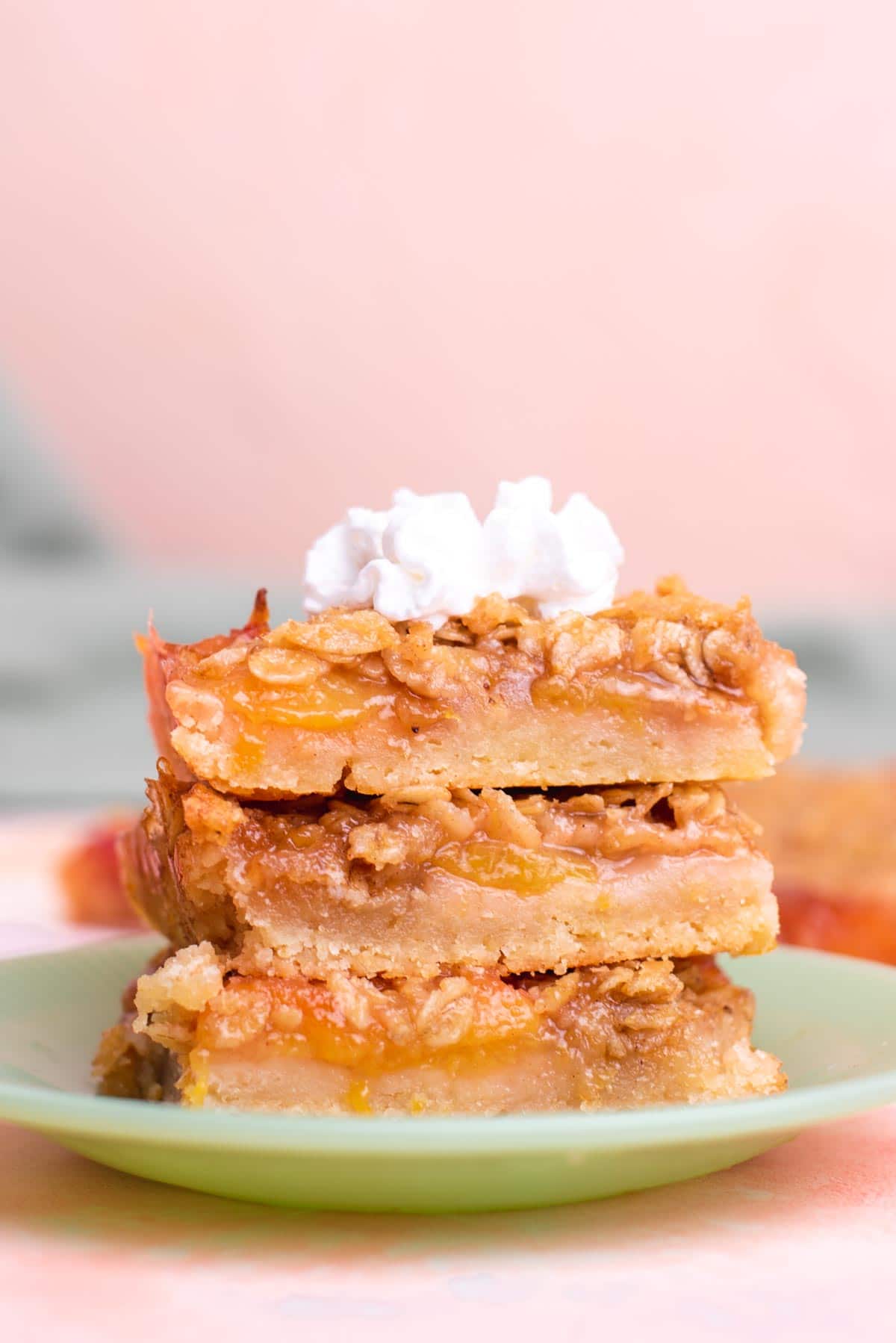 Three peach bars stacked on top of each other with a dollop of whipped cream on top