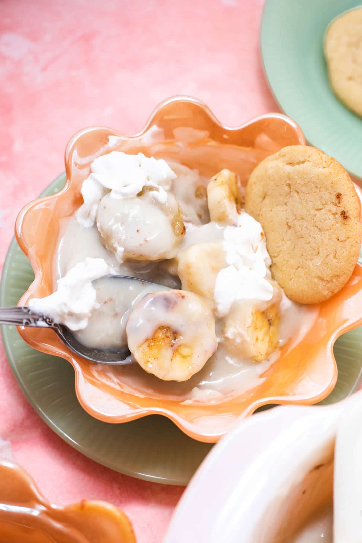Cloes up of spoon in vanilla pudding with sliced bananas and a cookie