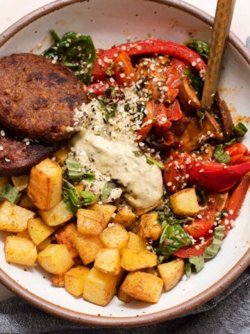 Overhead view of potatoes, veggies, sausages and goat cheese in a ceramic bowl