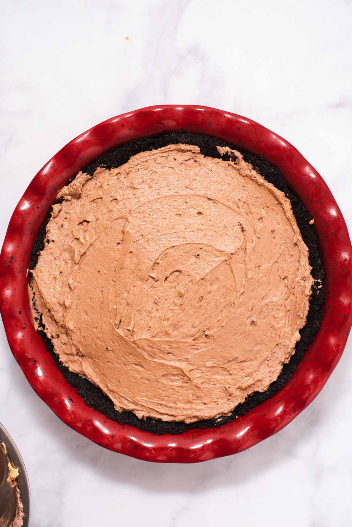 Overhead view of red pie dish filled with chocolate filling