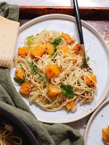 Overhead view of white plate with pile of angel hair pasta and butternut squash