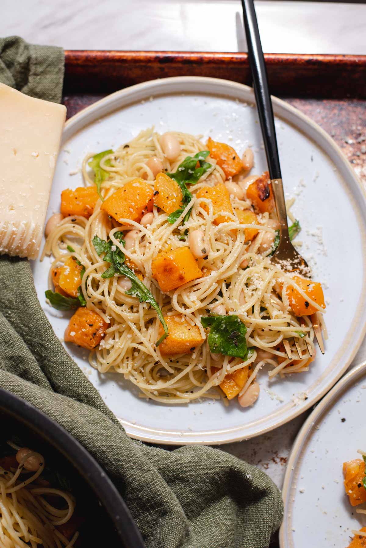 Overhead view of white plate with pile of angel hair pasta and butternut squash