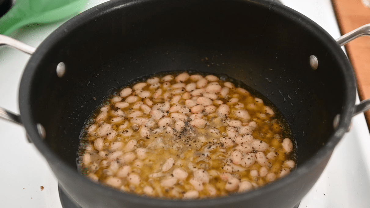 White beans in olive oil in a black Dutch oven.