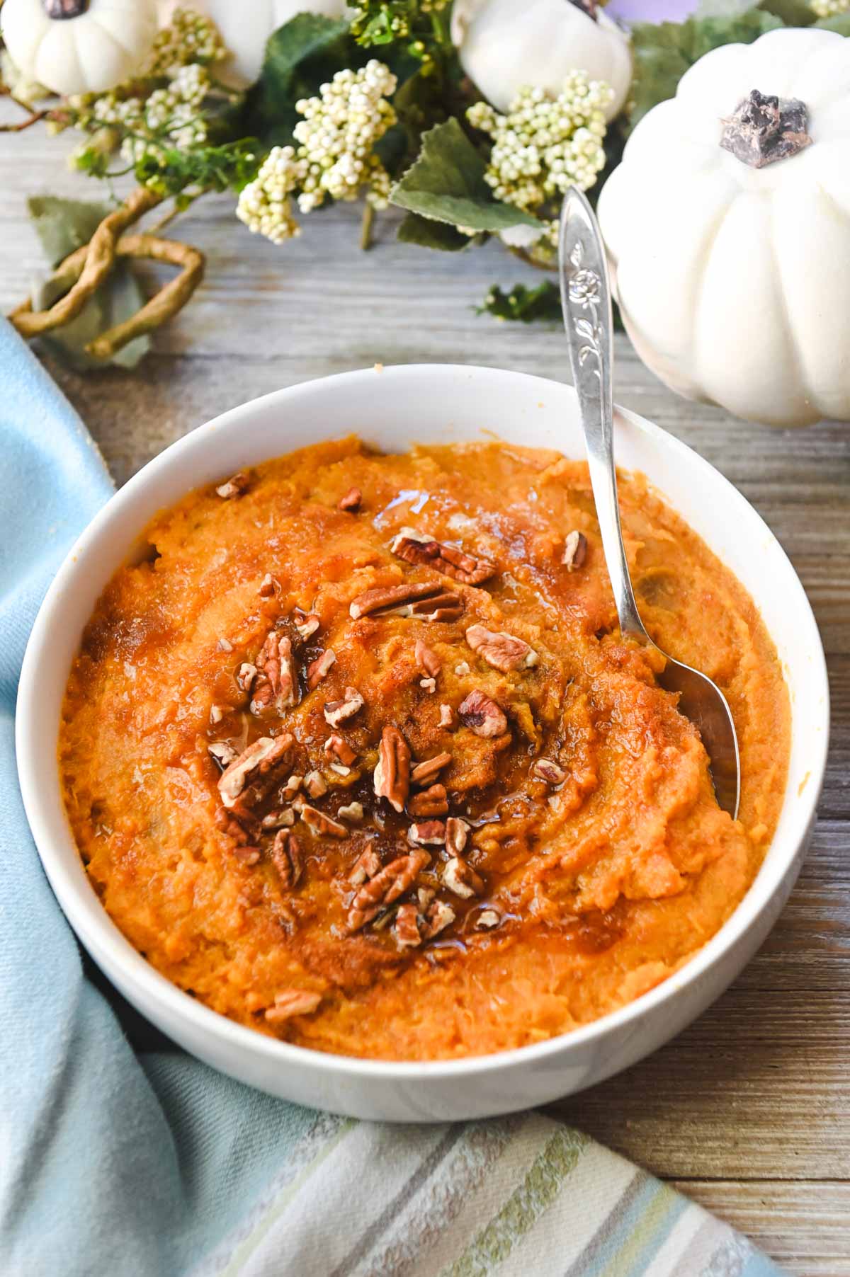 Side view of white bowl of mashed sweet potatoes on a blue cloth