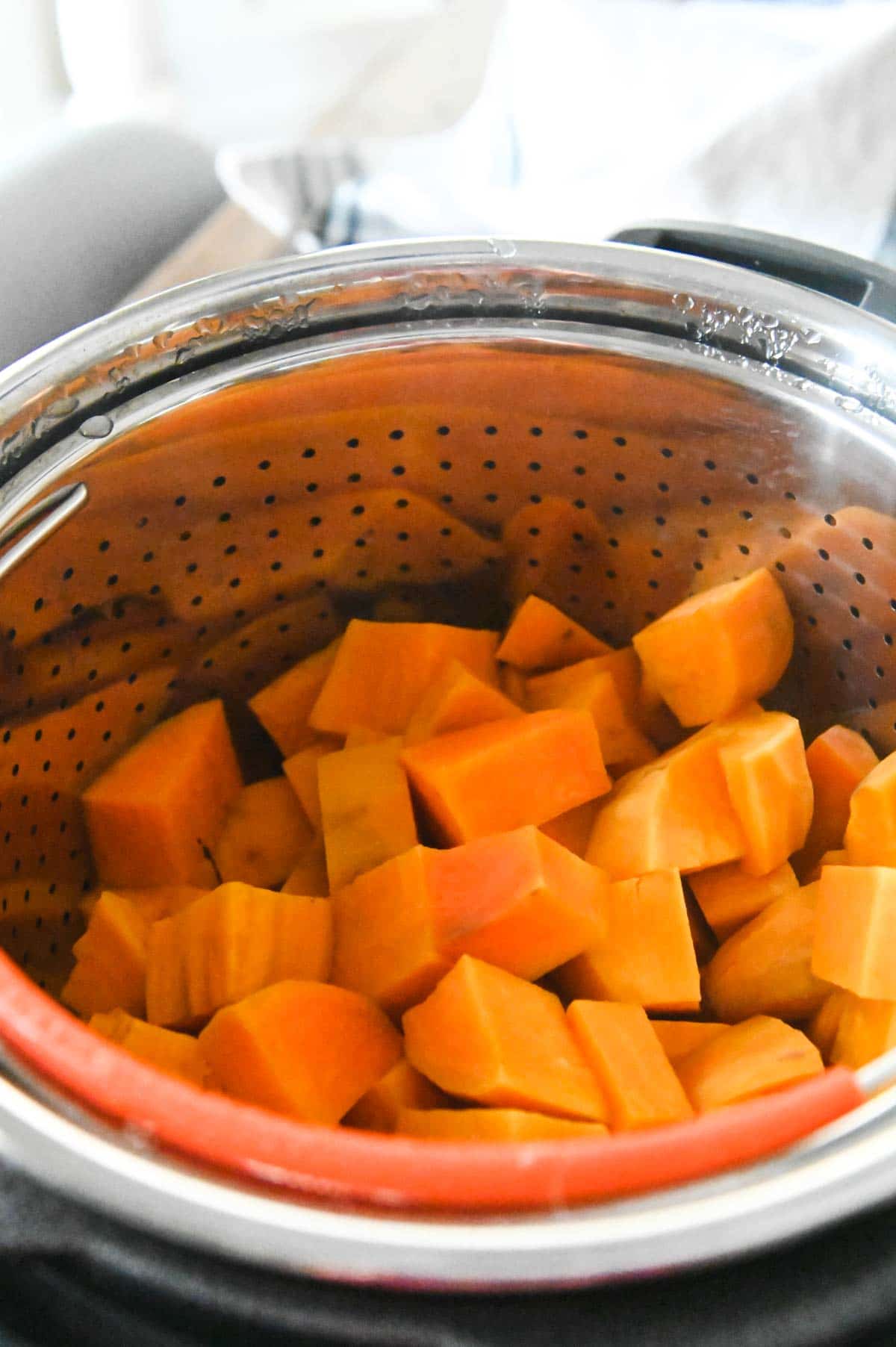 Cooked diced sweet potatoes in a steamer basket