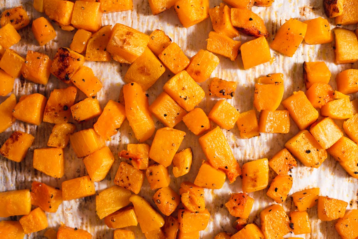 Close up of roasted butternut squash pieces on parchment paper