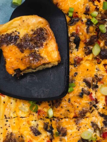 Overhead view of vegetarian breakfast casserole with slice of casserole resting on a black spatula.