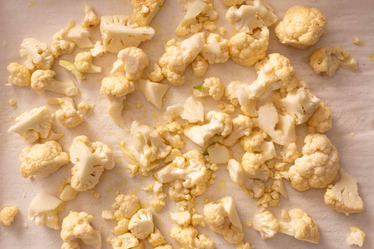 Cauliflower florets spread out on a parchment paper lined baking sheet