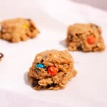 Scoop of cookie dough with orange M&M on white parchment paper