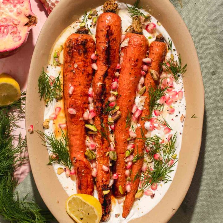 Four whole carrots on a bed of white whipped feta in a brown oval serving dish