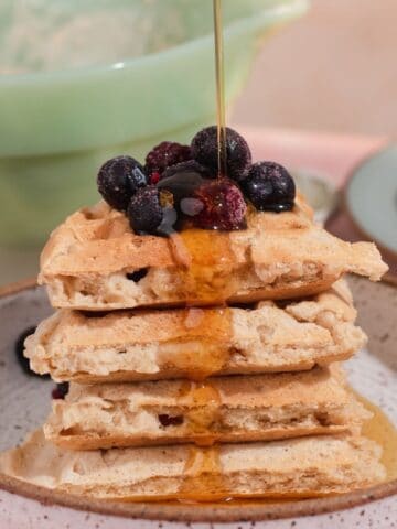 Stack of waffle pieces topped with blueberries and maple syrup.