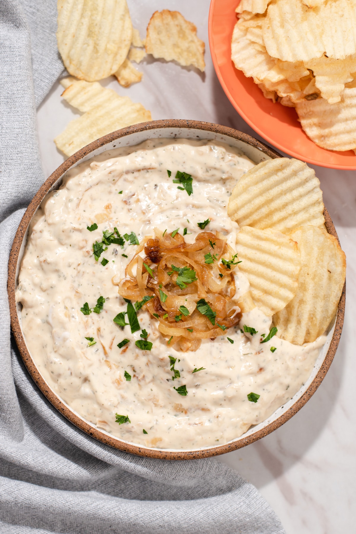 Overhead view of bowl filled with onion dip, caramelized onions, and potato chips.