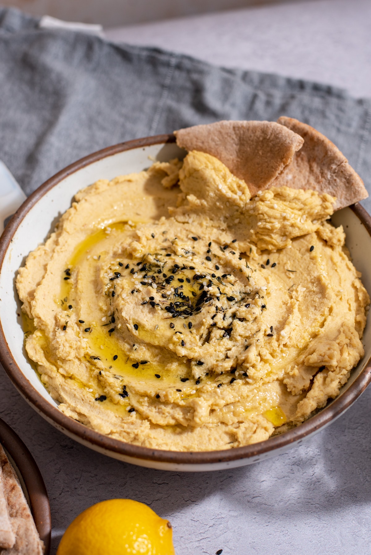 White bowl filled with hummus and pita bread.