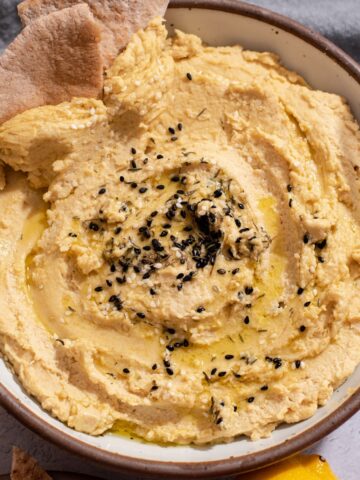 Overhead view of bowl with hummus and pita bread.
