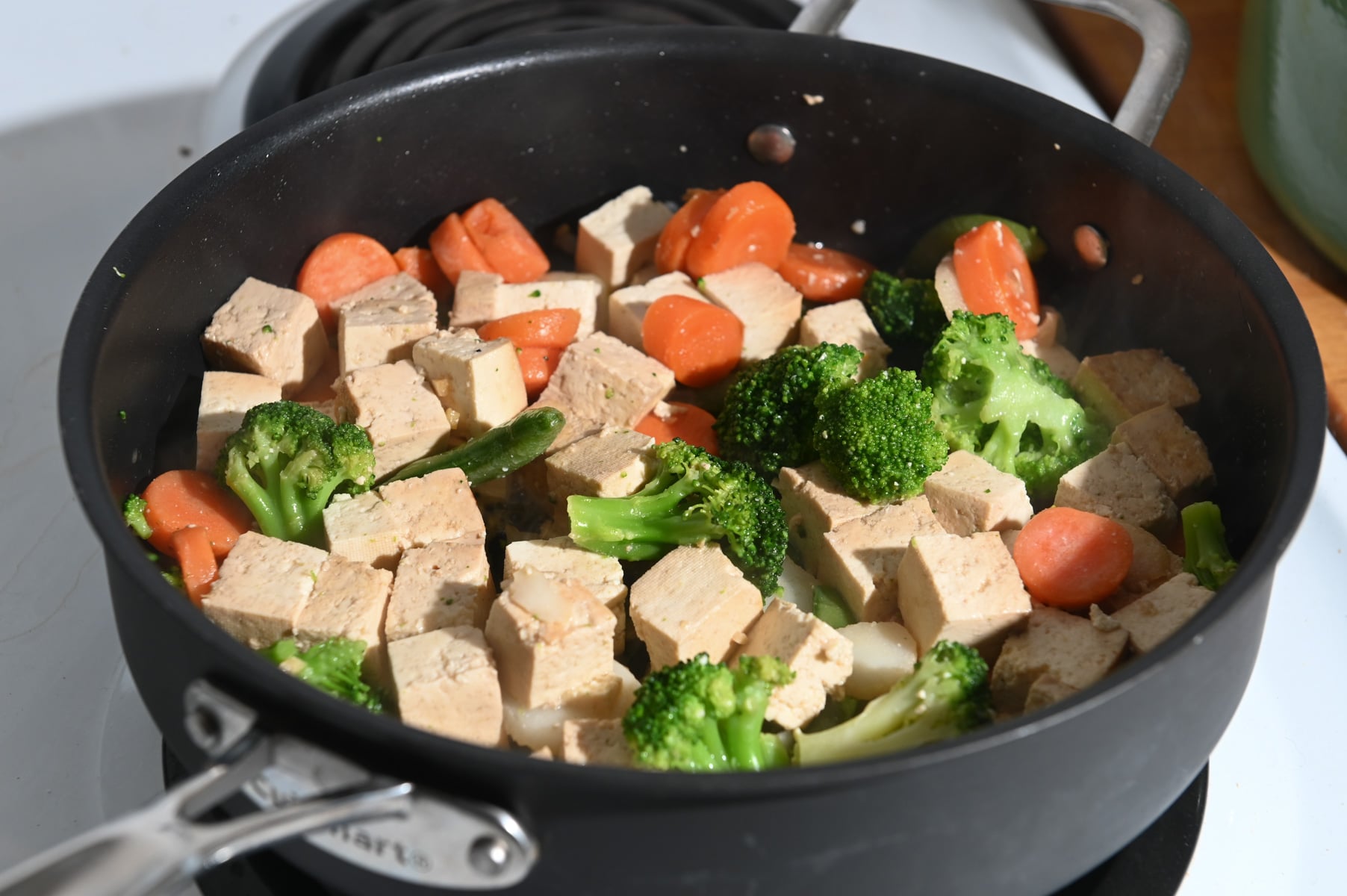 Diced tofu and vegetables in a black skillet.