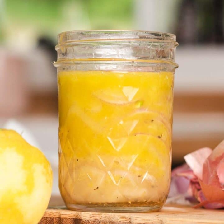 Glass jar filled with yellow vinaigrette.
