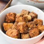 Close up of cubed tempeh in a white bowl.