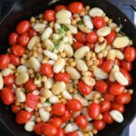 Roasted tomatoes and gnocchi in skillet.