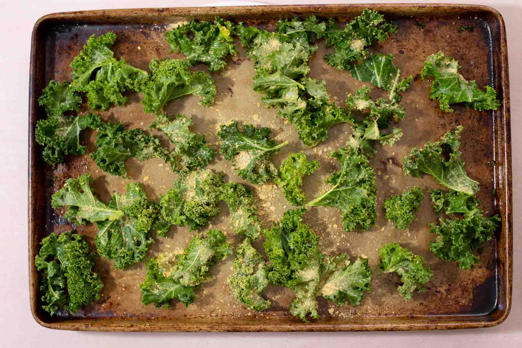 Kale pieces spread out on a baking sheet.