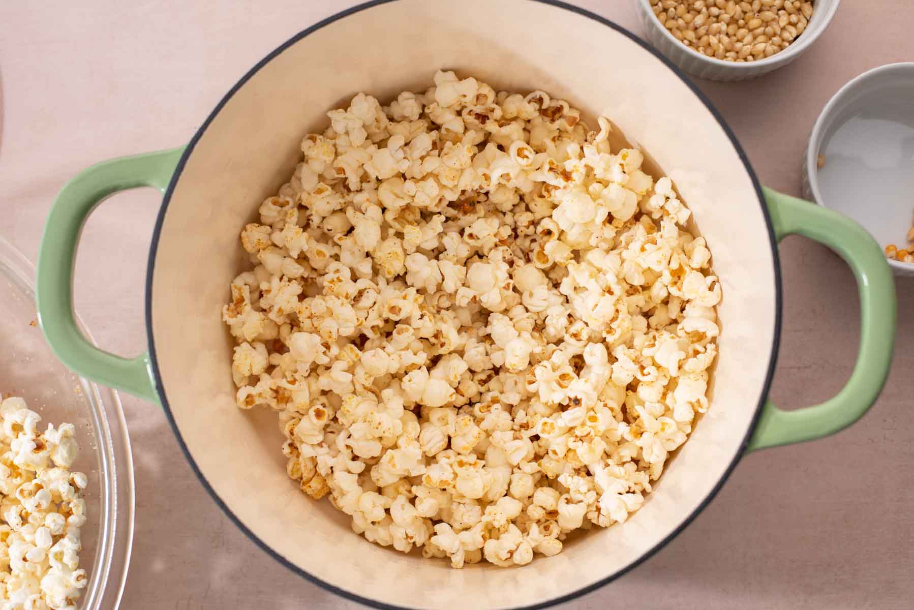 Large green Dutch oven filled with popped popcorn.